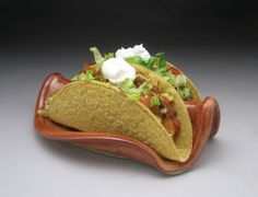 three tacos with lettuce, tomatoes and sour cream in a brown bowl