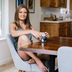 a woman sitting at a table with a cup in her hand