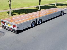 a large semi truck is parked on the side of the road in front of some trees