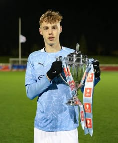 a young man holding a trophy on top of a soccer field