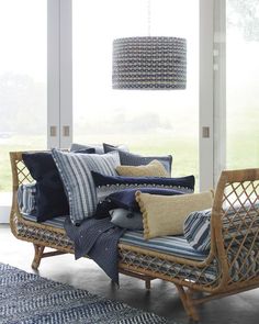 a wicker daybed with pillows and blankets on it in front of a window