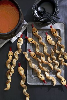 some kind of food that is on a tray next to a bowl and spoons