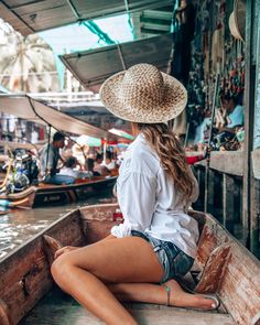 a woman sitting in the back of a boat on a river with lots of boats