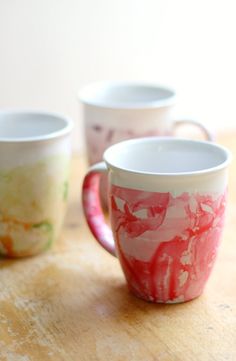 three coffee mugs sitting on top of a wooden table next to eachother