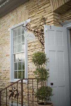 a door and window on the side of a building with a potted plant next to it