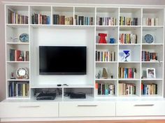 a white entertainment center with bookshelves and a flat screen tv mounted on the wall