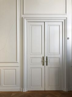 an empty room with two white doors and wood floors