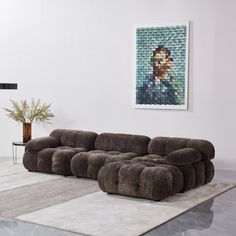 a large sectional sofa sitting on top of a rug in a living room next to a painting