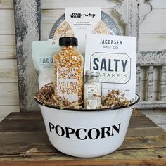 popcorn, salt and pepper shakers in a white bowl with the word salty written on it