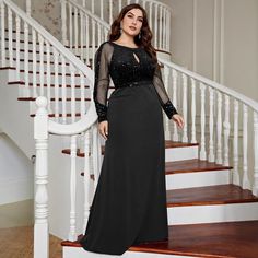 a woman in a long black dress standing on stairs