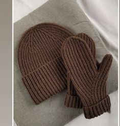 two brown mittens sitting on top of a pillow