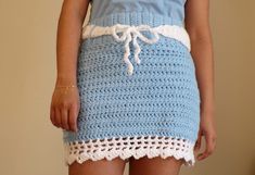 a woman wearing a blue and white crochet skirt with her hands in her pockets