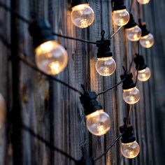 a string of light bulbs hanging from a wooden fence with lights on the outside and inside