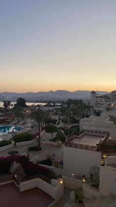 an aerial view of a resort and pool at dusk, with mountains in the background