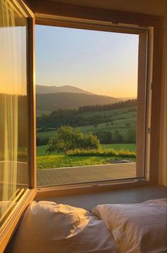 a bedroom with a large window looking out onto the countryside