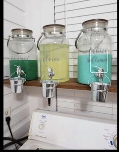 three glass jars with lids are sitting on a shelf above a washer and dryer