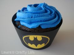 a cupcake with blue frosting and a batman sticker on the top is shown