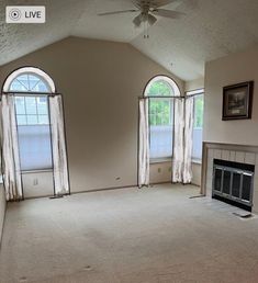 an empty living room with two windows and a fireplace in the middle of the room