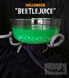 a green liquid in a glass bowl with black and white stripes on the bottom that says halloween beetlejuice