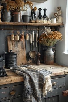 an old kitchen with many pots and pans on the shelves, flowers in vases