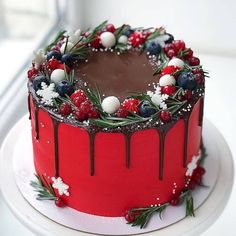 a red cake with chocolate frosting and berries