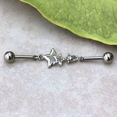 a metal barbell ring with three stars on it and two balls hanging from the end