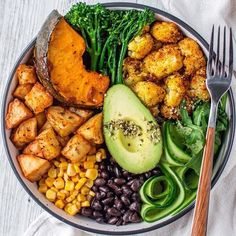 a plate filled with different types of food and a fork next to it on a white table