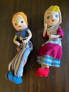 two dolls sitting next to each other on a table