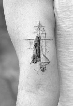 a black and white photo of a space shuttle tattoo on the left side of the arm