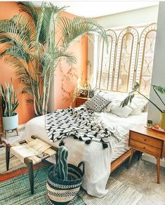 a bed room with a neatly made bed next to a potted plant