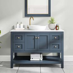 a bathroom vanity with blue cabinets and a white sink under a framed mirror above it