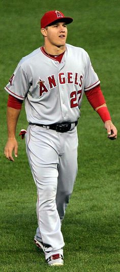 a baseball player is walking on the field with his foot in the air while wearing a red and grey uniform