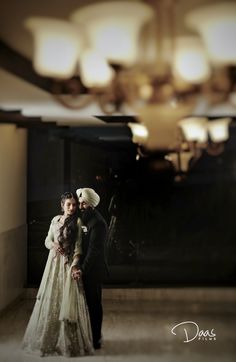 a man and woman standing next to each other in front of a chandelier