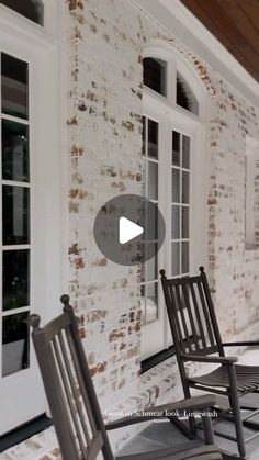 two rocking chairs sitting on top of a patio next to a brick wall and door