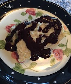 a piece of cake covered in chocolate sauce on a floral plate with polka dot border