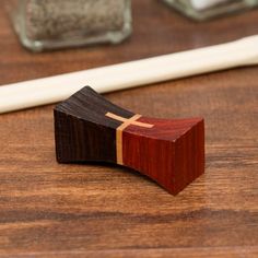 a wooden object with a cross on it sitting on a table next to a pen