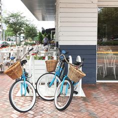 two bicycles parked next to each other in front of a building with tables and chairs