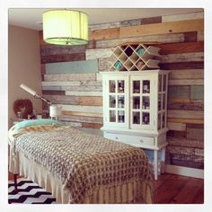 a bedroom with wood paneled walls and a bed in front of a dresser next to a lamp