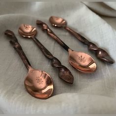 six antique spoons are lined up on a white cloth