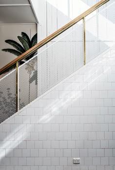 a man riding a skateboard down the side of a metal hand rail next to a white tiled wall