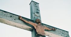 a man is on the cross with his hands in the air and he is wearing no shirt