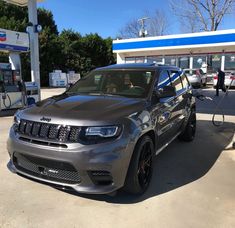 a jeep parked in front of a gas station next to a man filling up his car