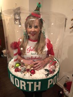 a woman in a north pole shirt under a snow globe with christmas decorations on it