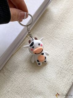 a hand holding a keychain with a cow on it