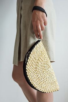 a woman holding a woven purse in her right hand