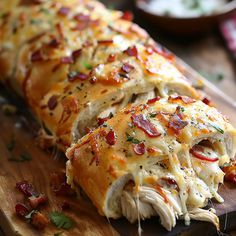 a cheesy roll with bacon and cheese on it sitting on a cutting board