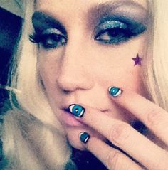 a blonde woman with blue eyes and stars on her nails is making a funny face