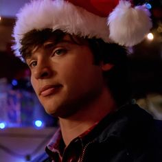 a young man wearing a santa hat with lights in the background