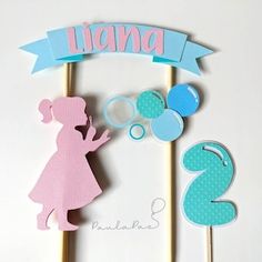 a cake topper with a girl holding a balloon and number two on it's stick