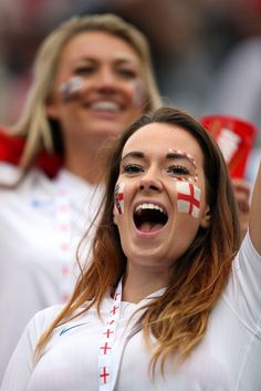 two women with england painted on their faces and one holding a cup in her hand